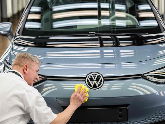 (FILES) An employee checks the surface of an Volkswagen (VW) ID 3 electric car of German carmaker Volkswagen, at the 'Glassy Manufactory' (Glaeserne Manufaktur) production site in Dresden, eastern Germany on June 8, 2021. The Volkswagen group, which is preparing an unprecedented savings plan, formalised on September 10, 2024 the termination of the employment guarantee agreement in force for thirty years in Germany, the first stage of negotiations that promise to be stormy with staff representatives. (Photo by JENS SCHLUETER / AFP)