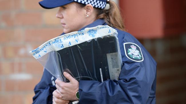 A laptop is taken from the Ascot Vale flats in an evidence bag. Picture: AAP