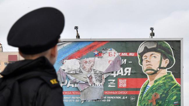 A military cadet stands in front of a billboard promoting contract army service in Saint Petersburg on October 5. Picture: AFP