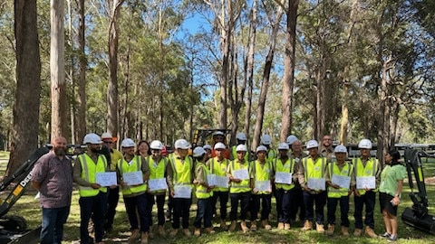 The cohort of 16 students, all former refugees, who have just completed a short course operating heavy machinery at Coffs Harbour TAFE.