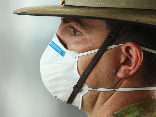 A member of the Defence Force wears a protective mask whilst waiting for returning overseas passengers at Sydney Airport.