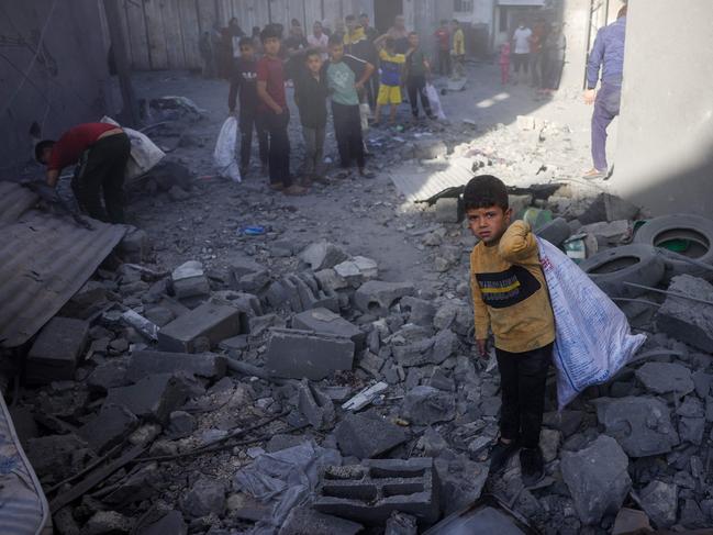 Children collect items as Palestinians check the site of an overnight Israeli strike, in Jabalia in the central Gaza Strip. Picture: AFP