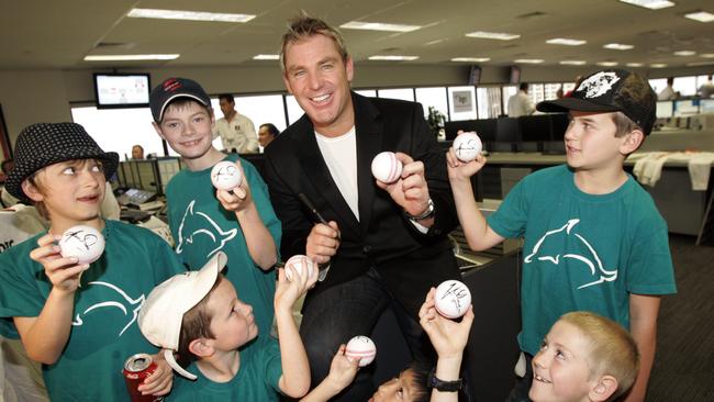 Kids show off cricket balls signed by Shane Warne at a charity day.