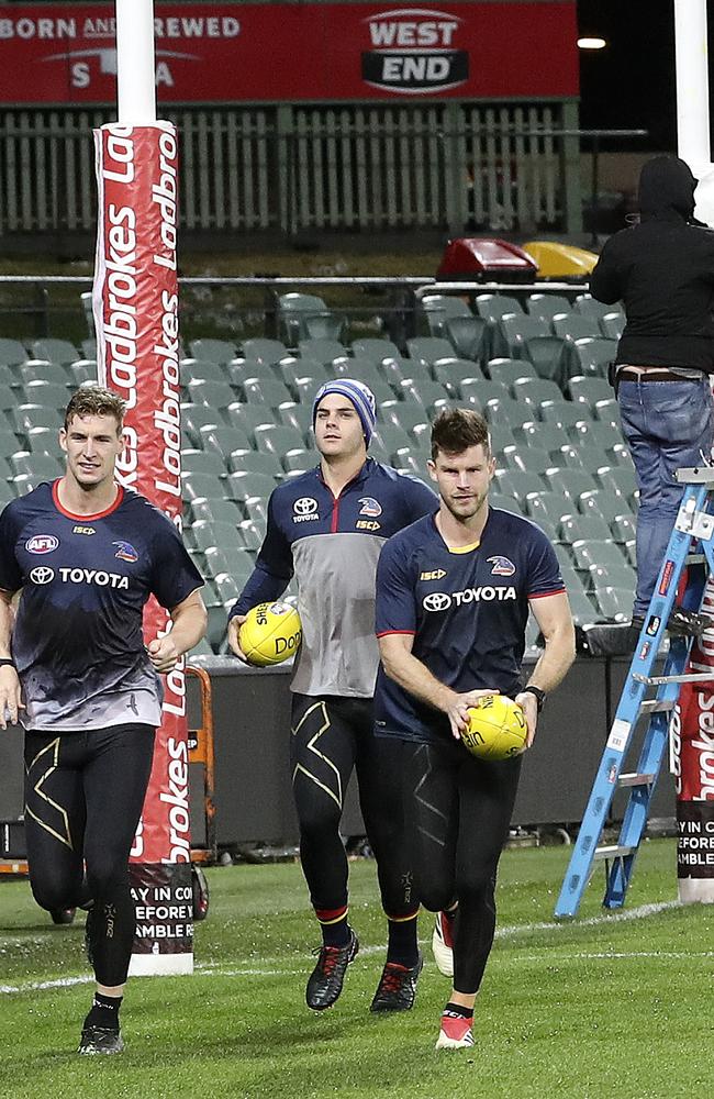 Ground staff work on the oval as the star Crows trio get some running into their legs. Picture: Sarah Reed.