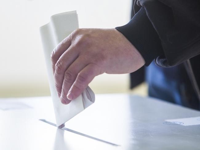 Hand of a person casting a ballot at a polling station during voting. election voting vote polling poll generic Townsville