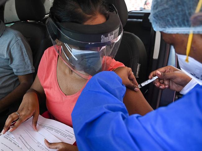 A health worker inoculates a woman with a dose of the Covaxin vaccine against Covid-19 at a drive-in vaccination centre in Moolchand hospital in New Delhi. Picture: AFP