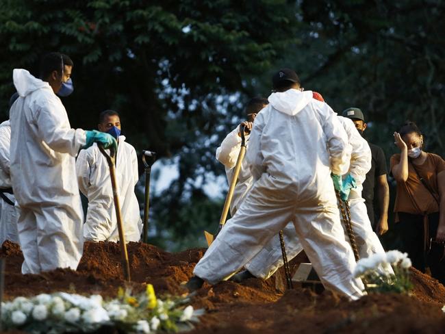 People mourn as a relative is buried by cemetery workers in protective gear as a preventive measure against the spread of the novel coronavirus disease, COVID-19, at the Vila Formosa cemetery in Sao Paulo, Brazil, on April 17, 2021. - The number of people who have died worldwide in the Covid-19 pandemic has surpassed three million. The worldÃÂ¢Ãâ¬Ãâ¢s Covid-19 death toll surpassed three million on Saturday, according to Johns Hopkins University. (Photo by Miguel SCHINCARIOL / AFP)