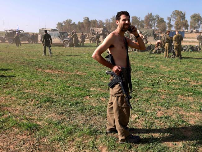 An Israeli soldier speaks on the phone as Israeli troops gather near the border with the Gaza Strip in Israel after their return from the Gaza Strip. Picture: AFP