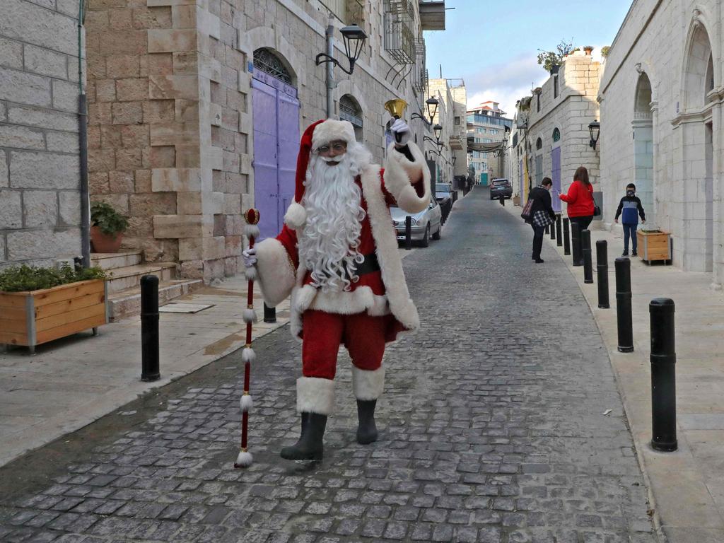 A Palestinian man dressed as Santa Claus walks along an almost deserted street in the occupied West Bank town of Bethlehem, ahead of Christmas. Picture: AFP