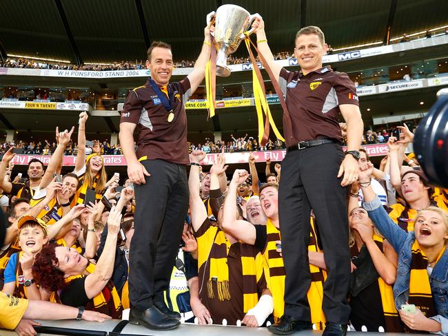 Hawthorn coach Alastair Clarkson (left) and assistant coach Brendon Bolton get their hands on the cup. Picture: Wayne Ludbey