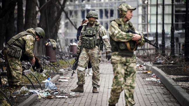 Russian soldiers walk along a street in Mariupol.