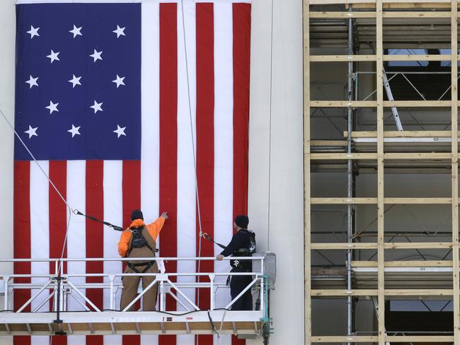 Workers install a flag outside the US Capitol in Washington, before a rehearsal of President-elect Donald Trump's swearing-in ceremony. Picture: AP