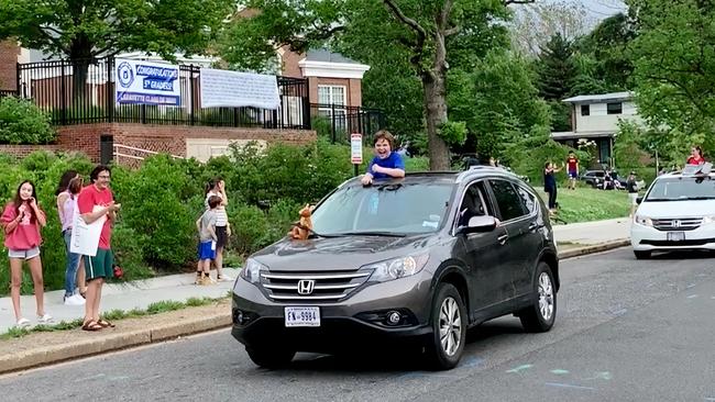 Laughter returns to the streets: Young Tobias, riding in the car with the kangaroo, celebrates his virtual graduation with a real-life drive-by at Lafayette Elementary in Washington DC. Picture: Cameron Stewart