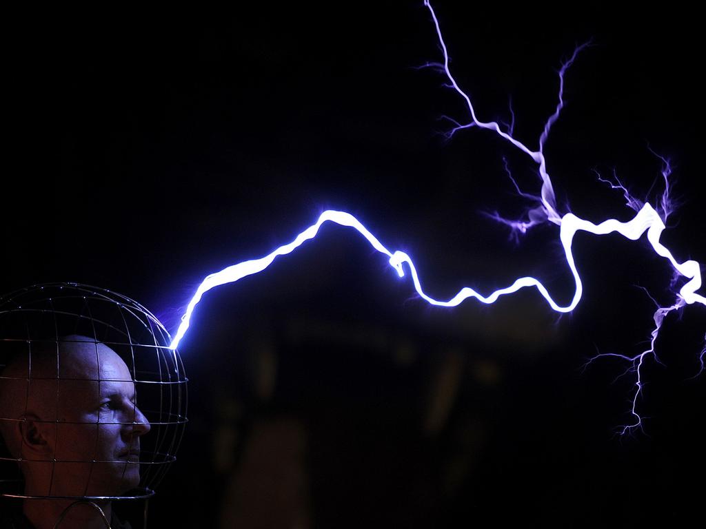 Oleg Melnik, wearing a wire helmet, getting electrical discharges of Tesla coil inside a Faraday cage at the Elemento Science Museum in Minsk. / AFP / SERGEI GAPON