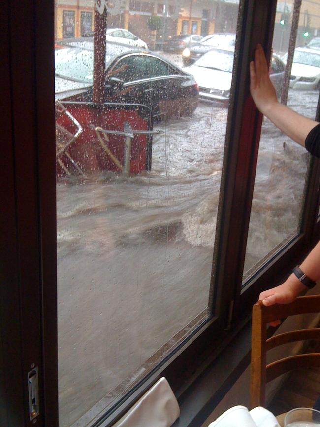 The street flowing at Camberwell Junction in 2011. The cafe furniture is being washed away. Picture: HWT Library.