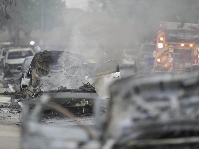 Vehicles are damaged as authorities work the scene where a small plane crashed into a San Diego neighbourhood. Picture: AP/Gregory Bul.