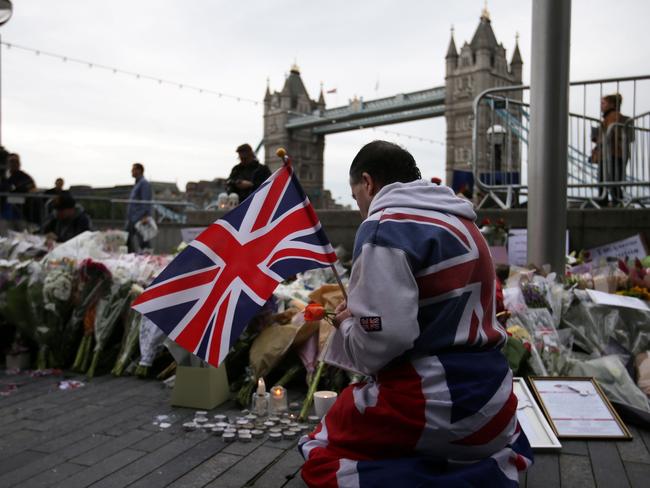 A man holds a Union flag as he kneels near flowers layed at Potters Fields Park in London during a vigil to commemorate the victims of the terror attack on London Bridge and at Borough Market that killed seven people. Picture: AFP / Daniel LEAL-OLIVAS