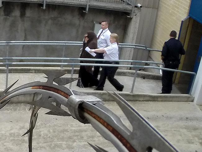 The South Australian woman is taken to the Adelaide Magistrates Court from the watch-house by security officers. Picture: Greg Higgs