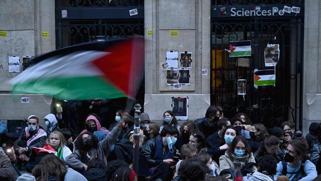 A protester waves a Palestinian flag as they stage a sit-in in front of French riot policemen near the entrance of a Institute of Political Studies (Sciences Po Paris) building occupied by students, in Paris. Picture: AFP