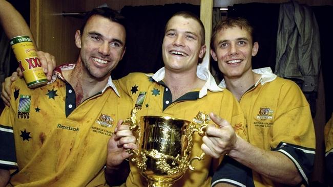 Joe Roff, Ben Tune and Stephen Larkham celebrate the World Cup win wearing the traditional gold jersey Picture: Getty Images