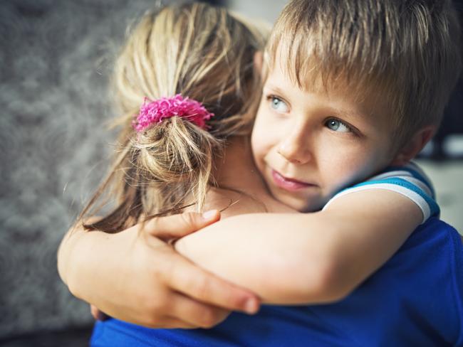 Closeup of happy little boy aged 5 embracing his mother. The mother and boy are lit by soft light from the window.