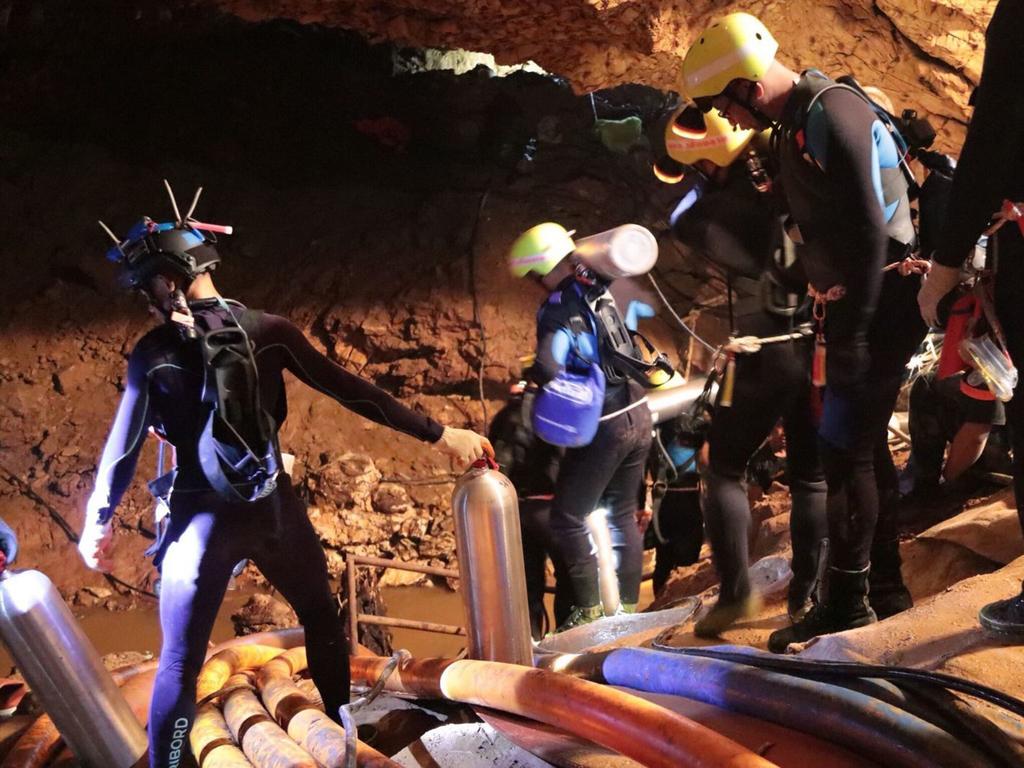 Thai rescue team members walk inside a cave where 12 boys and their soccer coach have been trapped since June 23. Picture: Royal Thai Navy via AP