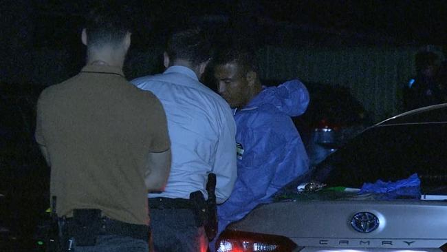 A man in a blue forensic suits talks to police at the scene. .