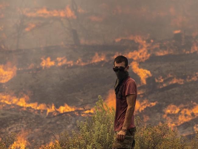 A man stands ready to fight flames as they engulf a hillside in Apollana, Rhodes, Greece. Picture: Dan Kitwood/Getty Images