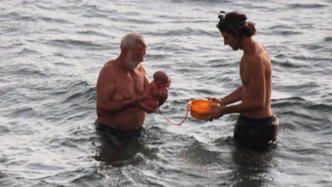 A husband and doctor hold a baby after it was delivered in the sea. Picture: Hadia Hosny El Said/CEN/australscope