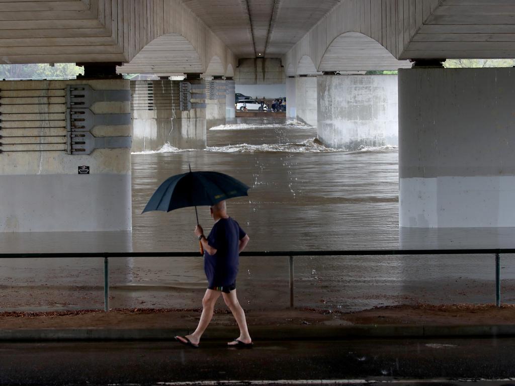 A man holds an umbrella as he looks at the rising flood waters under the Nepean Bridge at Regentville. Picture: Toby Zerna