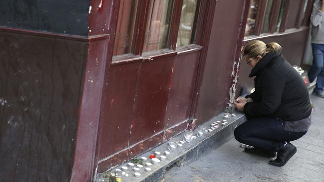 A woman leaves candles outside of the Carillon bar in the 10th district of Paris.