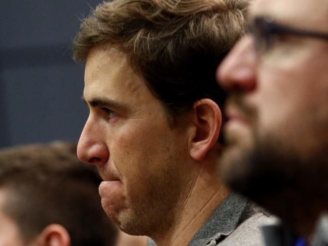 New York Giants quarterback Eli Manning, center, reacts while listening to former head coach Tom Coughlin speak during a news conference, Tuesday, Jan. 5, 2016, in East Rutherford, N.J. (AP Photo/Julio Cortez)