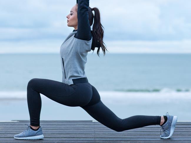 Beautiful brunette woman stretching on a seafront wearing sports clothes as a warming up exercise istock image