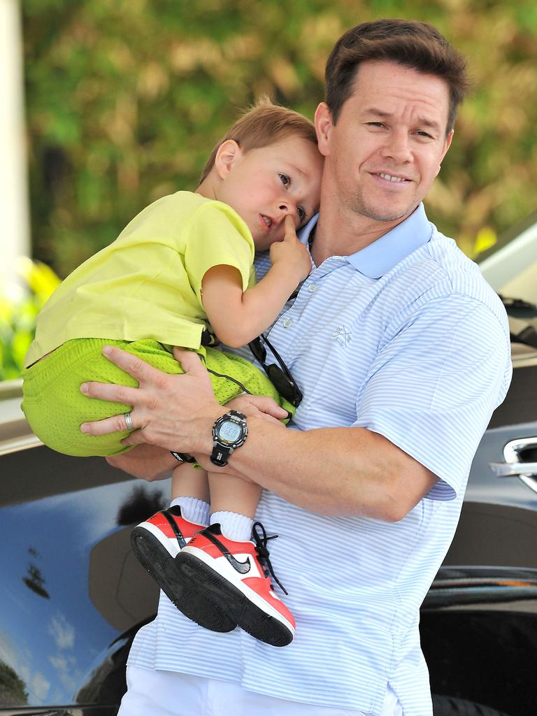 Fossicking ... Mark Wahlberg carries son Brendan — who is otherwise preoccupied — on a day out in Miami. Picture: Australscope