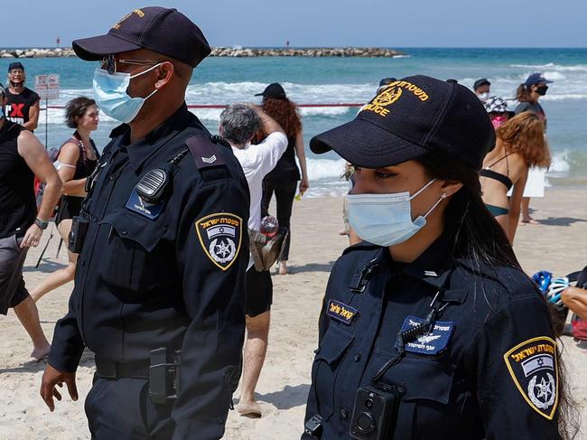 Israeli police officers patrol a beach as people demonstrate in the coastal city of Tel Aviv to protest the government's decision to close beaches during the lockdown due to the COVID-19 pandemic, on September 19, 2020. - Israel imposed a second nationwide lockdown to tackle one of the world's highest coronavirus infection rates, despite public protests over the new blow to the economy. The three-week shutdown started hours before Rosh Hashana, the Jewish New Year, and will extend through other key religious holidays, including Yom Kippur and Sukkot. (Photo by JACK GUEZ / AFP)