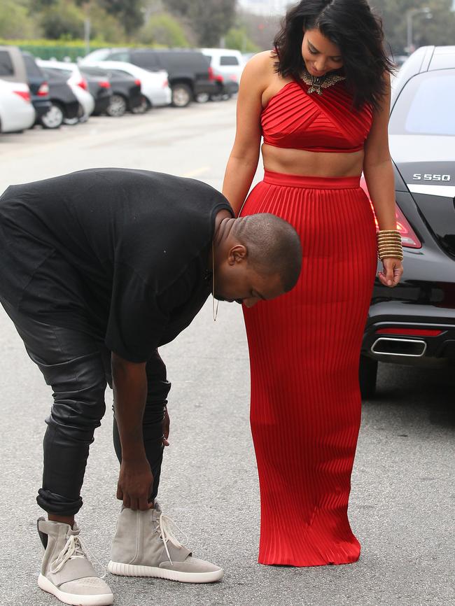 Kanye stops to adjust his custom Yeezy shoes.