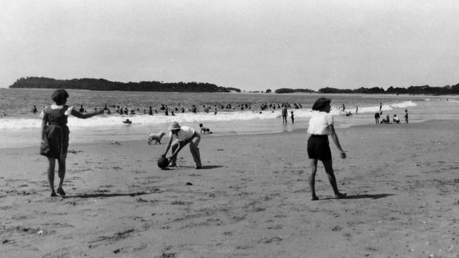 Beach goers enjoying the surf and foreshore at Mooloolaba Beach during the Christmas holiday period, ca 1940.