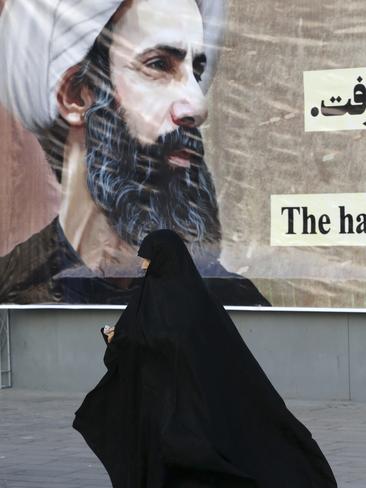 An Iranian woman walks past a portrait of Sheikh Nimr al-Nimr, a prominent opposition Saudi Shiite cleric, who was executed by Saudi Arabia. Picture: AP