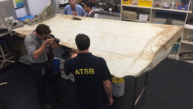 Close inspection. A wing part found in Tanzania is inspected by ATSB experts. Picture: AFP/ATSB