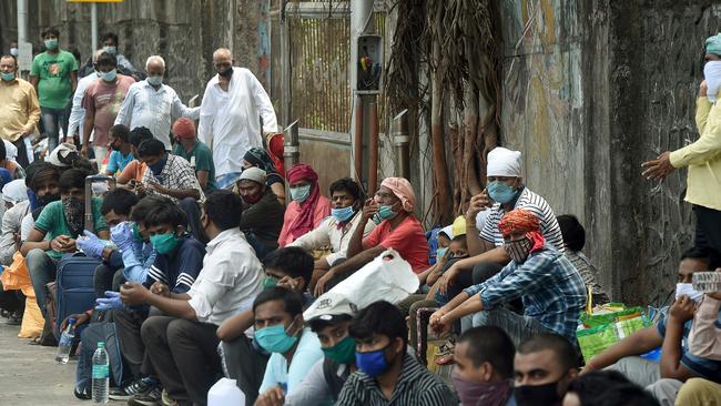 Migrant workers wait outside the Chhatrapati Shivaji Maharaj Terminus railway station to return to their hometowns after the government eased a nationwide lockdown as a preventive measure against the COVID-19 coronavirus, in Mumbai.