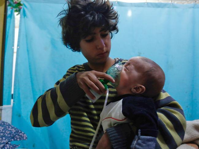 A Syrian boy holds an oxygen mask over the face of an infant following a reported gas attack. Picture: AFP