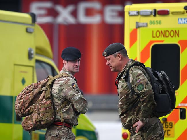 Members of Britain's armed forces stand by London Ambulances in a car park at the EXCEL London exhibition centre, which has been transformed into a field hospital. Picture: AFP)