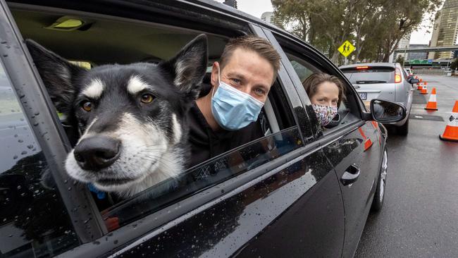 Chris Halshaw, Jenny Salisbury and their dog Dante line up in their car at the Covid testing site in Montague Street, South Melbourne. Picture: David Geraghty