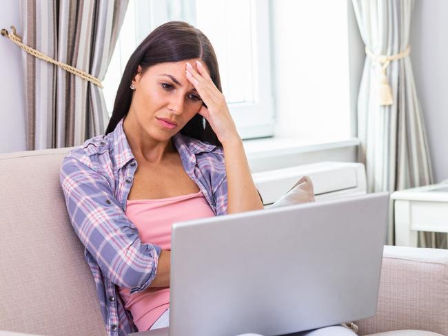 Young frustrated woman working from home in front of laptop ; confused investor generic.