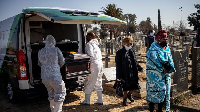 Relatives observe undertakers unloading a casket containing the remains of a COVID-19 coronavirus patient during a funeral at the Avalon cemetery in Soweto. Picture: AFP