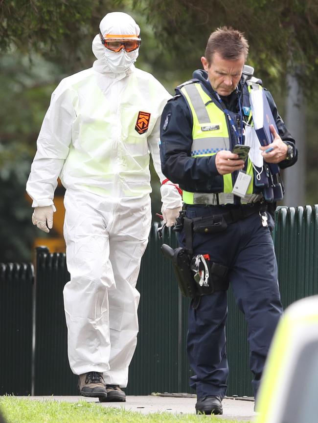 A man in protective walks with a police officer outside the Flemington towers. Picture: David Crosling