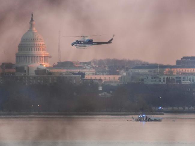 A helicopter flies near the crash site of the American Airlines plane on the Potomac River after the plane crashed on approach to Reagan National Airport. Picture: Getty Images via AFP