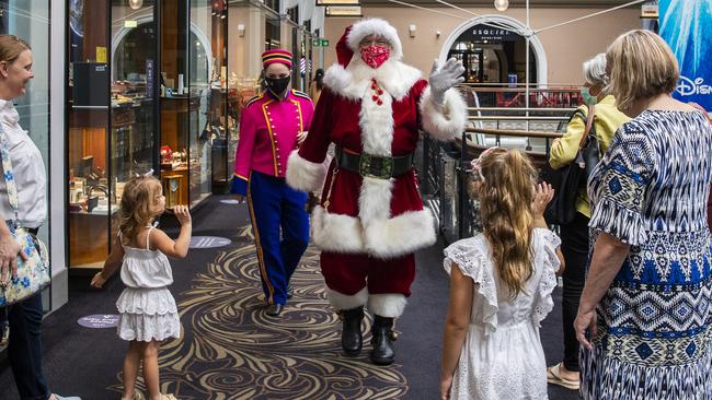 A masked Santa Claus waves to people in The Queen Victoria Building in the Sydney CBD. Picture: Jenny Evans/Getty Images