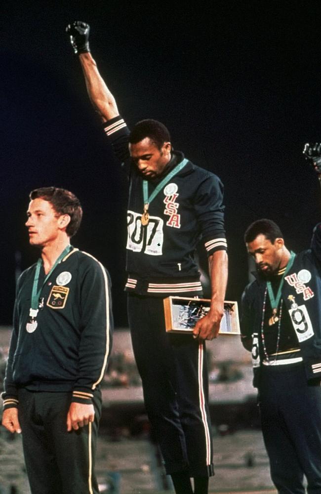 In an iconic stand, US athletes Tommie Smith, centre, and John Carlos, right, stare down at the ground during the playing of the national anthem and make a Black Power salute at the 1968 Mexico City Olympic Games. Picture: AP Photo