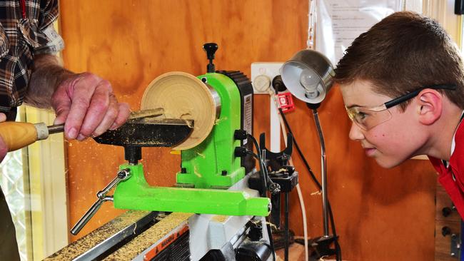 Liam from The Field Trip watches John Newell from the Men’s Shed turn a wooden bowl on a lathe. Picture: Dennis Manktelow